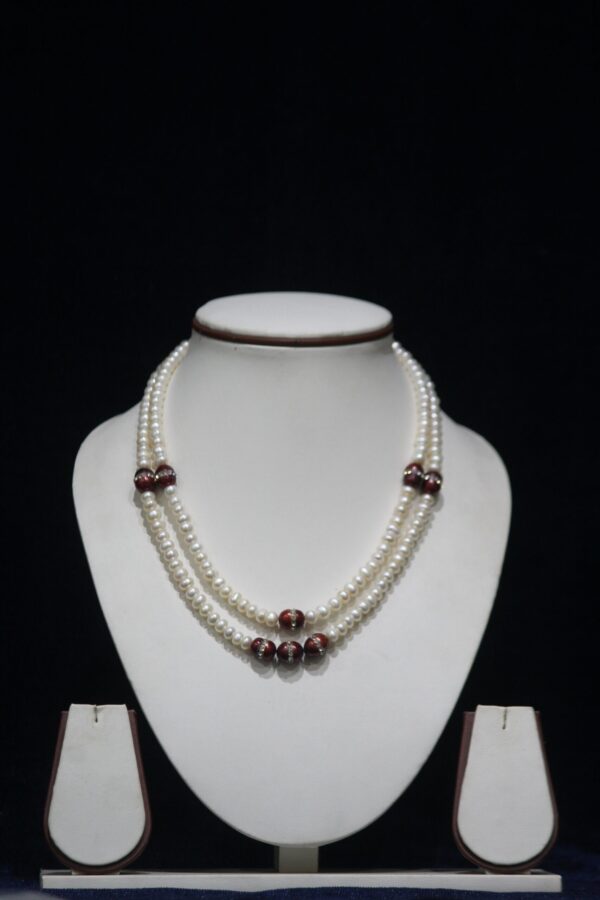 Pearl Necklace Set with Red Stone Accents - A luxurious necklace featuring luminous pearls paired with vibrant red stones, complemented by matching earrings.