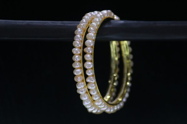 Traditional pearl bangle featuring lustrous pearls on an ornate metallic band, perfect for cultural and festive occasions.