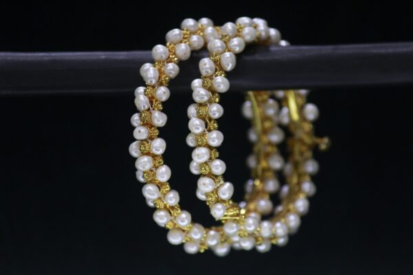 Elegant pearl bangles featuring lustrous pearls set on polished metallic bands, designed to add timeless charm and sophistication to your look.