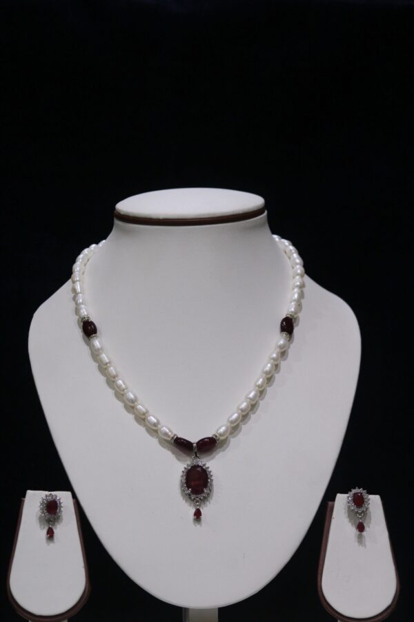 Pearl necklace set with a vibrant garnet pendant, featuring lustrous pearls paired with a deep red garnet for a luxurious and timeless design.