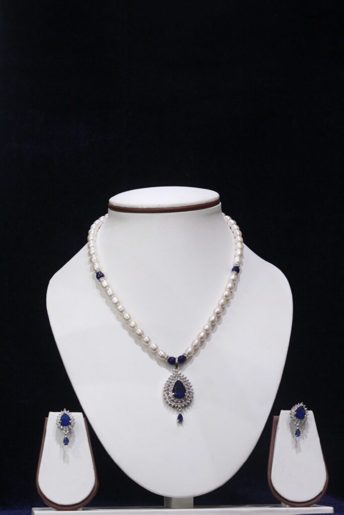 Pearl necklace set with a stunning blue stone pendant, featuring lustrous pearls and an elegant design for a timeless, sophisticated look.
