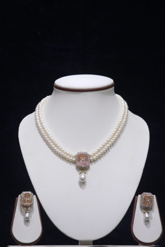 Two-layered pearl necklace set with a stunning pink stone pendant for an elegant look.