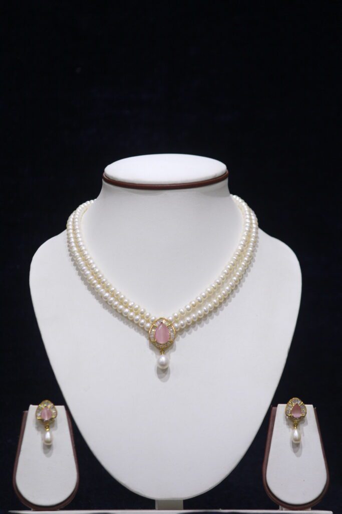 Two-layered pearl necklace set with a pink stone pendant, combining the timeless elegance of pearls with the delicate charm of a pink gemstone.