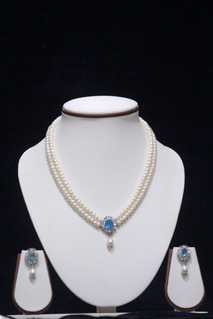 Two-layered pearl necklace set with a blue stone pendant, combining the timeless beauty of pearls and the vibrant elegance of a blue stone.