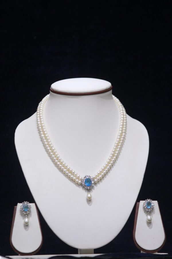 Two-layered pearl necklace set with a blue stone pendant, combining the timeless beauty of pearls and the vibrant elegance of a blue stone.