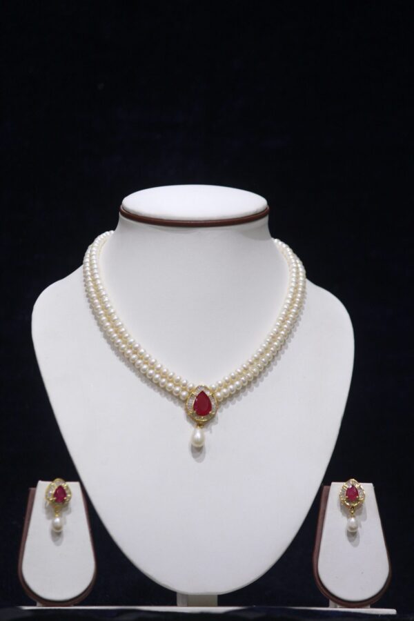 Two-layered pearl necklace set with a ruby pendant, combining classic pearls and a vibrant ruby for timeless elegance.