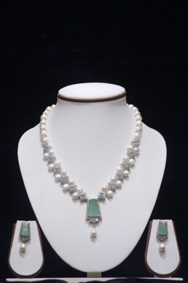 Elegant pearl necklace set featuring a striking green stone pendant, with matching earrings, offering a sophisticated and timeless design.