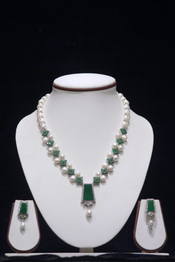 Elegant pearl necklace set with a stunning emerald pendant, perfect for adding a touch of luxury and sophistication to any special occasion.