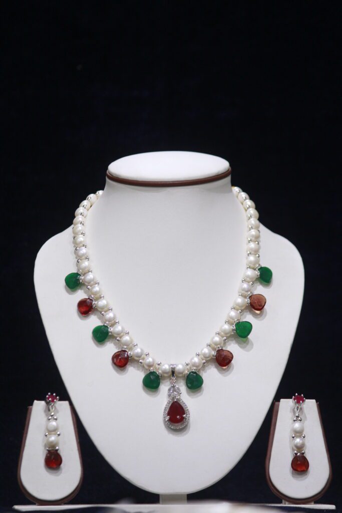 Pearl necklace set with ruby and emerald accents, offering a luxurious and vibrant touch to your jewelry collection.