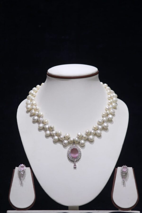 Three-layered pearl necklace set with pink stone pendant, showcasing elegant and vibrant design.