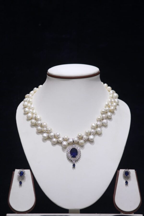Two-layered pearl necklace set with blue stone pendant, showcasing elegant design with vibrant blue stone for a sophisticated look.