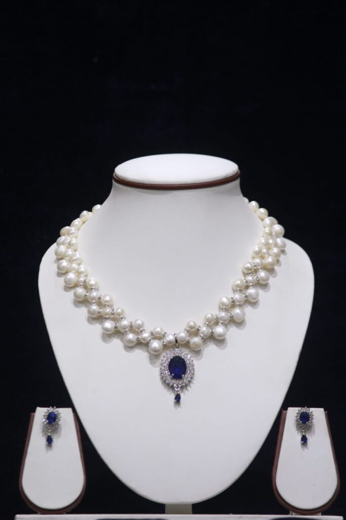 Two-layered pearl necklace set with blue stone pendant, showcasing elegant design with vibrant blue stone for a sophisticated look.