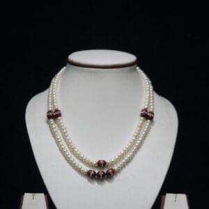 Pearl Necklace Set with Red Stone Accents - A luxurious necklace featuring luminous pearls paired with vibrant red stones, complemented by matching earrings.