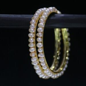 Traditional pearl bangle featuring lustrous pearls on an ornate metallic band, perfect for cultural and festive occasions.