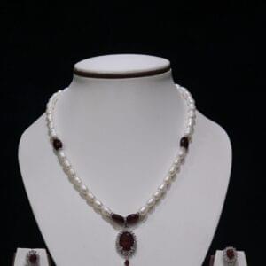 Pearl necklace set with a vibrant garnet pendant, featuring lustrous pearls paired with a deep red garnet for a luxurious and timeless design.