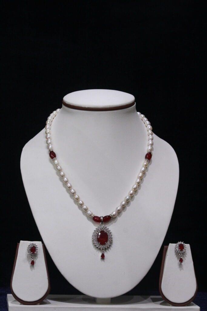 Pearl necklace set with a vibrant ruby pendant, featuring lustrous pearls and an exquisite design for timeless sophistication and elegance.