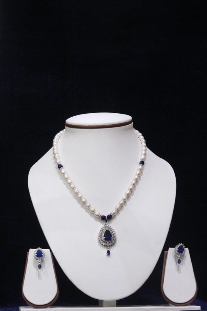 Pearl necklace set with a stunning blue stone pendant, featuring lustrous pearls and an elegant design for a timeless, sophisticated look.