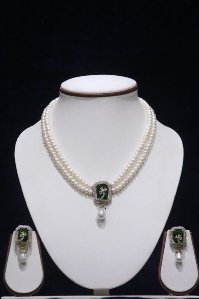 Two-layered pearl necklace set with a green stone pendant, combining the classic elegance of pearls with the vibrant touch of a green gemstone pendant.