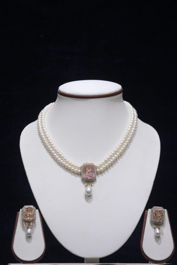 Two-layered pearl necklace set with a stunning pink stone pendant for an elegant look.