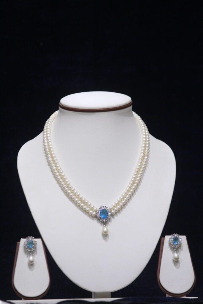 Two-layered pearl necklace set with a blue stone pendant, combining the timeless beauty of pearls and the vibrant elegance of a blue stone.