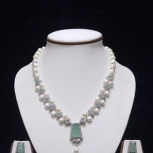 Elegant pearl necklace set featuring a striking green stone pendant, with matching earrings, offering a sophisticated and timeless design.