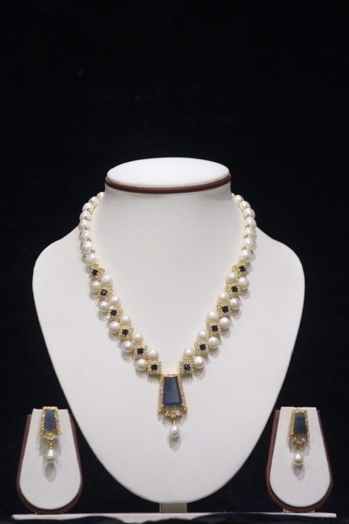 Elegant pearl necklace set with a beautiful blue stone pendant, adding a touch of color and sophistication to any outfit.