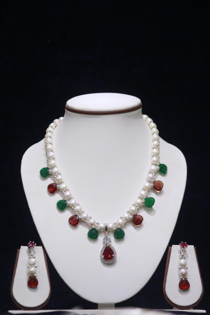Pearl necklace set with ruby and emerald accents, offering a luxurious and vibrant touch to your jewelry collection.