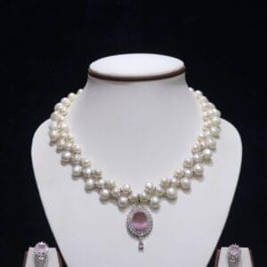 Three-layered pearl necklace set with pink stone pendant, showcasing elegant and vibrant design.