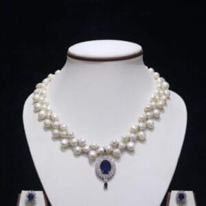 Two-layered pearl necklace set with blue stone pendant, showcasing elegant design with vibrant blue stone for a sophisticated look.