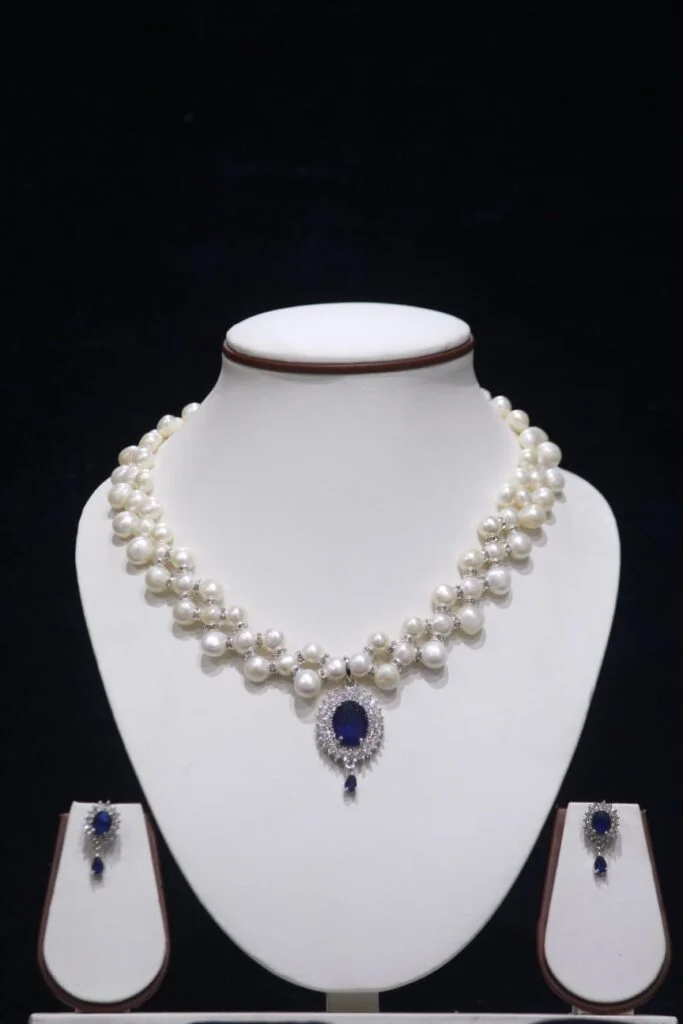 Two-layered pearl necklace set with blue stone pendant, showcasing elegant design with vibrant blue stone for a sophisticated look.
